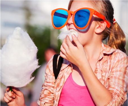 Ein Kind mit übergroßer Brille isst Zuckerwatte.